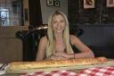 Kate Ovens begins her challenge to eat a saugsauge roll which is - three feet long. Picture: SWNS