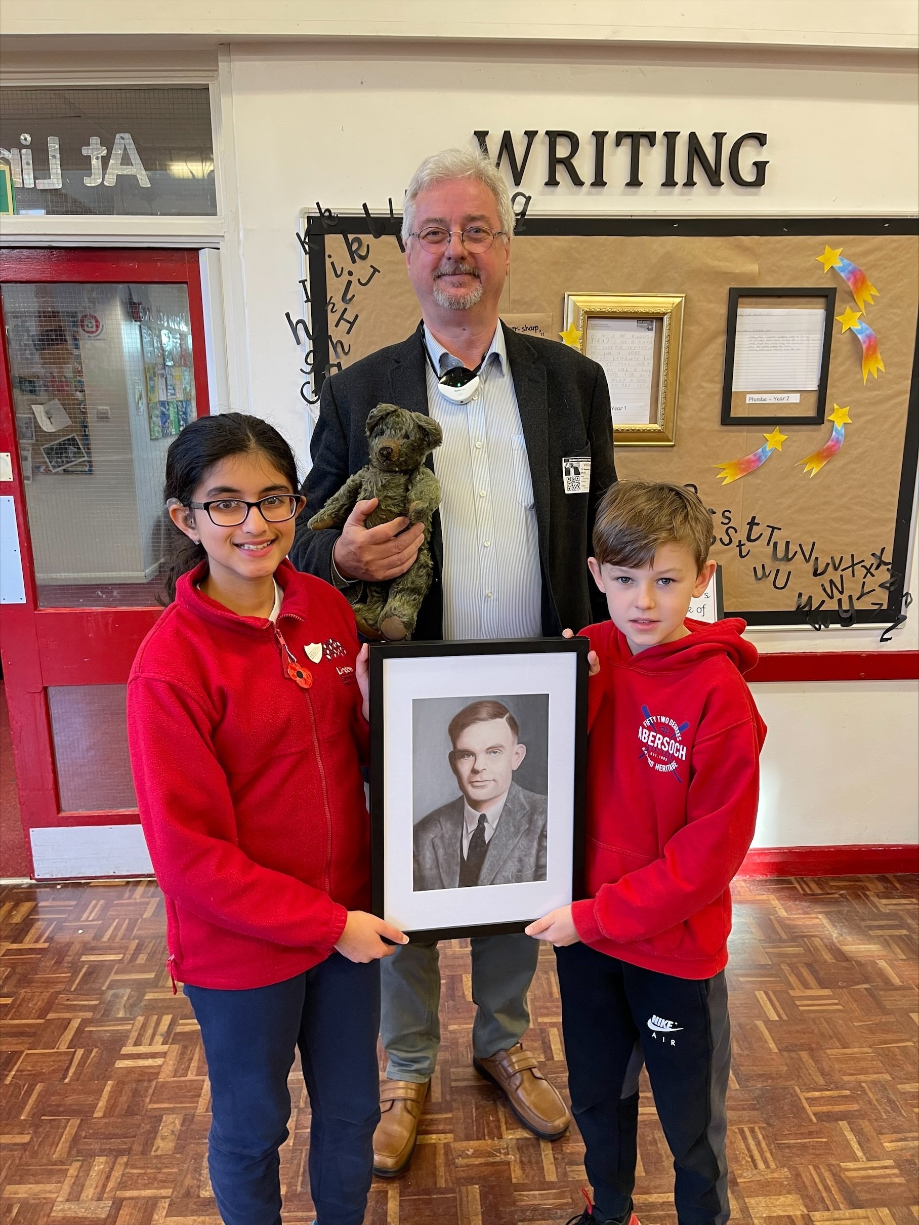 David Briggs, chairman of Wilmslow Historical Society presents a portrait of Alan Turing to head girl Gautami Sarseshpande and head boy Benjamin Holder