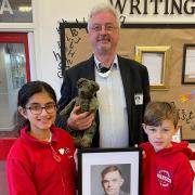 David Briggs, chairman of Wilmslow Historical Society presents a portrait of Alan Turing to head girl Gautami Sarseshpande and head boy Benjamin Holder