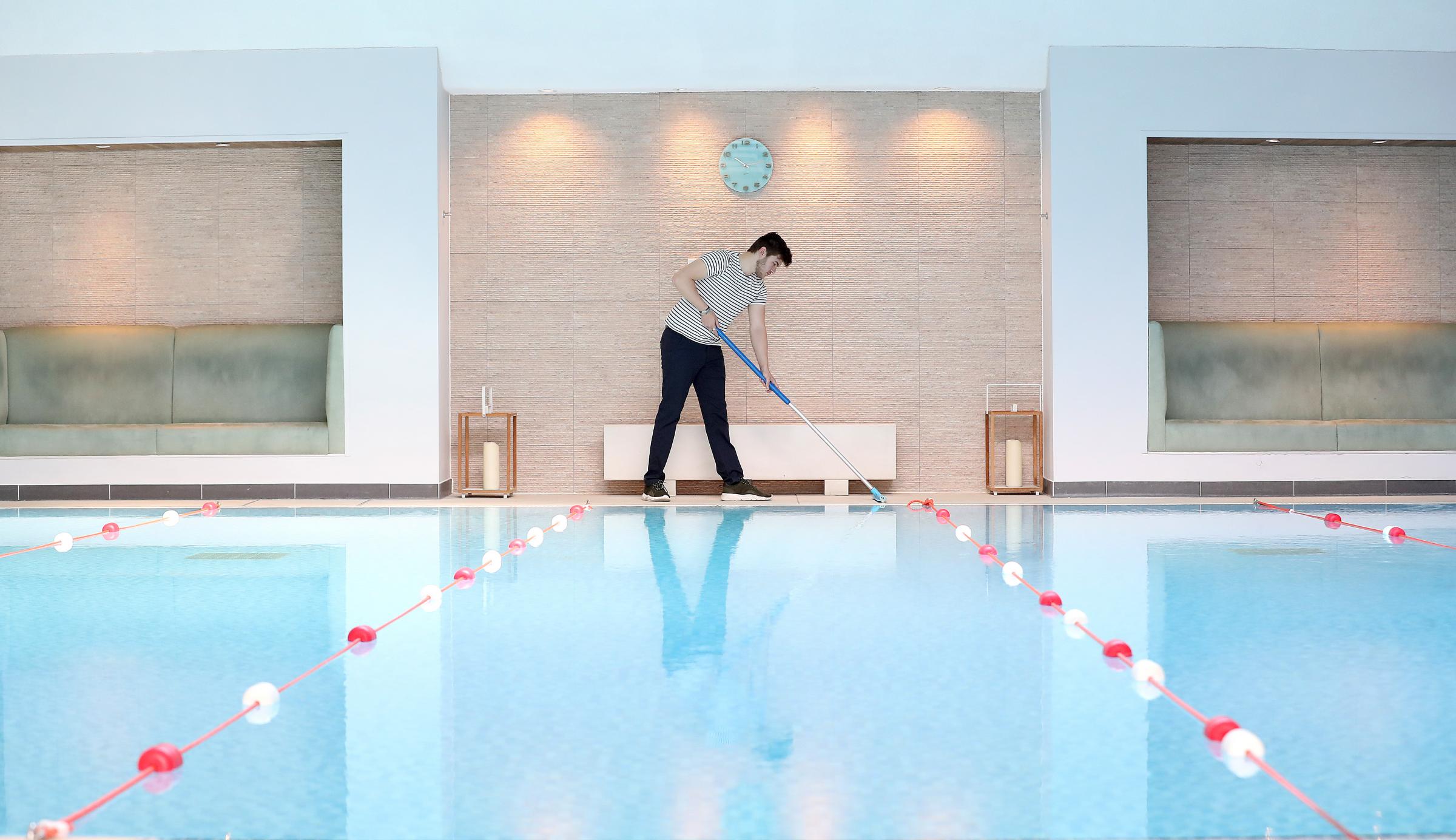 Spa assistant Kieran Wilson prepares the pool for socially distanced swimming at Cottons Hotel and Spa - PA Images