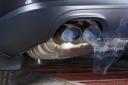 Exhaust pipe of a car - blowing out the pollution. Exhaust pipe coming out of the car with its exhaust. View from below, see the bottom of the exhaust pipe silver. Visible rear bumper eclipse of gray..