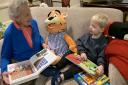 Retired teacher Margaret McKinley, 91,  reads Mr Happy,  a bedtime story, to two-year-old George Dainey