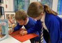 Pupils Lewis Johnson and Florence Fildes write personal messages to the royal family in a  condolence book at Bexton Primary School Picture: Bexton Primary School