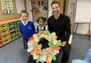 Gethin Jones, from BBC's The One Show with pupils Rayan Paul and Krisha Argwal and a memorial wreath made by the children