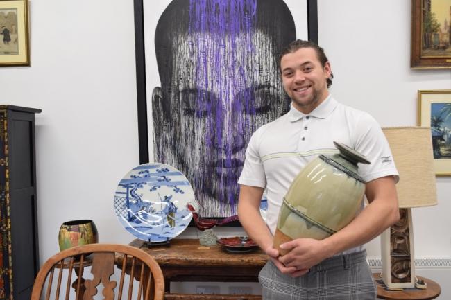 Ben Whittaker holding a Richard Batterham bottle vase as he stands in front of an 1830s Chinese elm altar table at his new shop