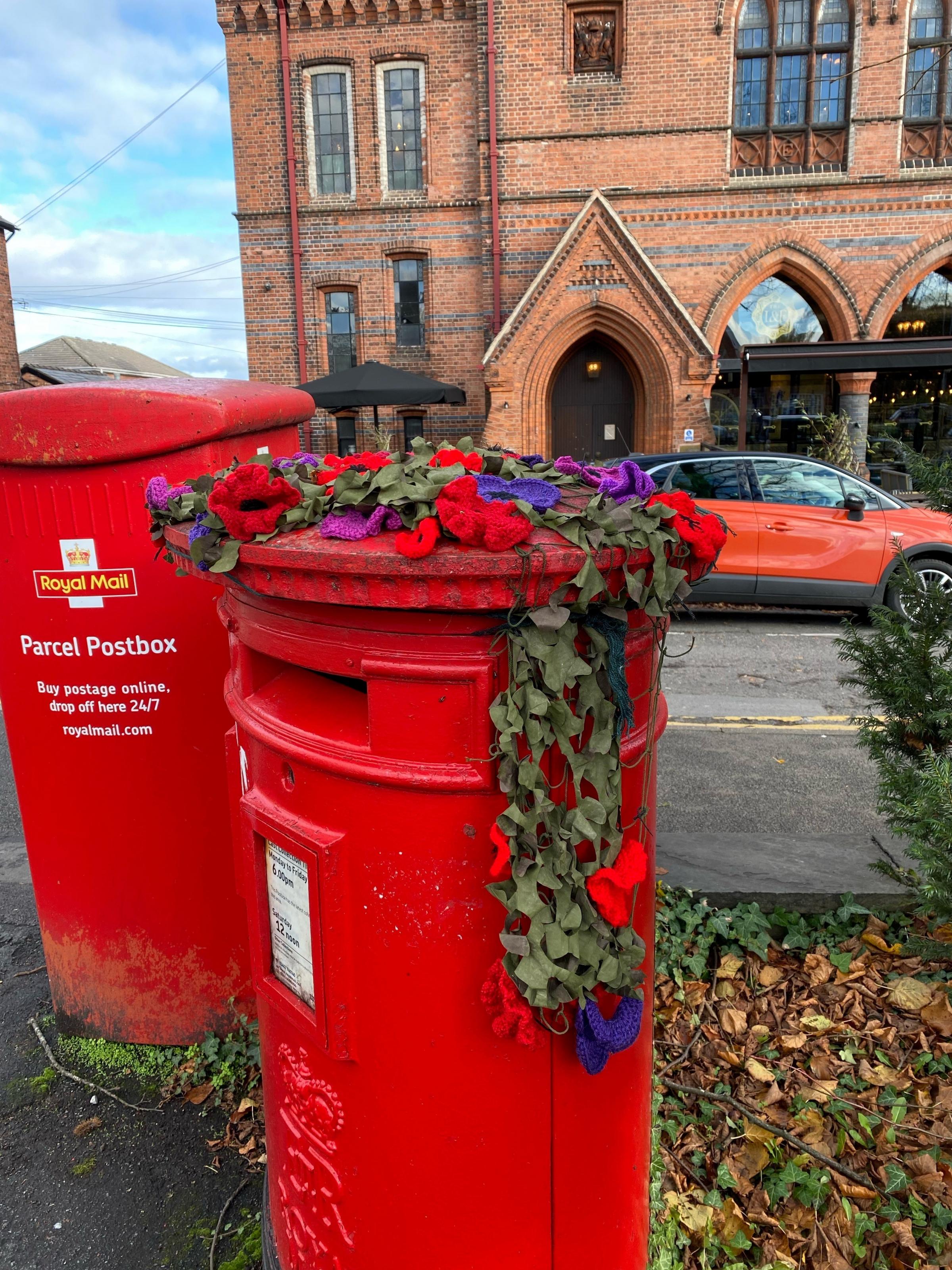 Some poppies are draped over a post box