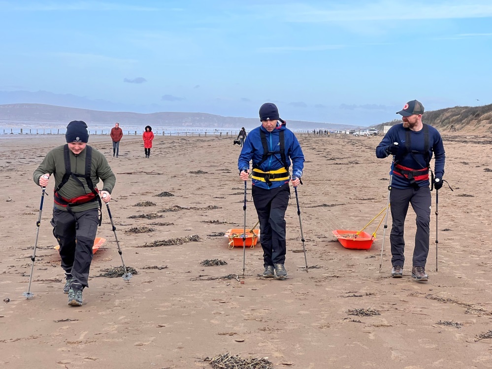 Rob, centre, pulling a sled along the beach in training