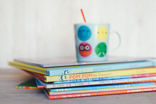 Knutsford Guardian: Children's books in a pile with a colourful mug on top. Credit: Canva