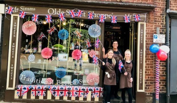Knutsford Guardian: Julia Chard, Charlotte Tims and Emma Routs waving flags outside the Olde Sweet Shoppe