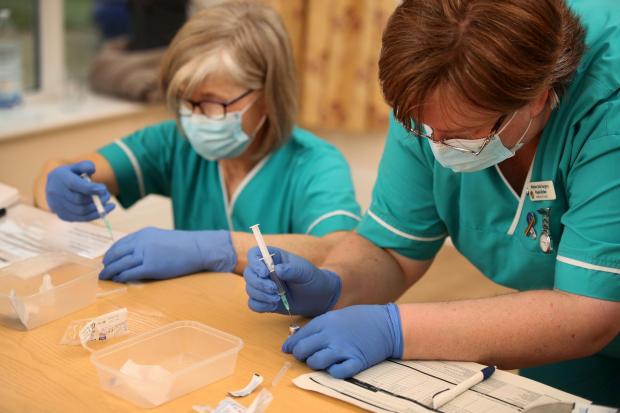 Health care assistant Paula Kirlew (right) and Nurse Helen Abbatt (left) prepares the BioNTech/Pfizer Covid-19 vaccine for doctors to administer