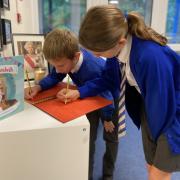 Pupils Lewis Johnson and Florence Fildes write personal messages to the royal family in a  condolence book at Bexton Primary School Picture: Bexton Primary School