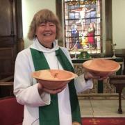 Rev Heather Buckley with an offertory plate and a holy water bowl made by local wood turner David Webb from wood salvaged from a juniper tree taken down in the churchyard